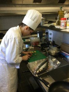 Etudiante d'école hôtelière cuisinant du poisson